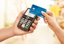 Empreendedor segurando cartão de crédito e analisando documentos financeiros em pequena empresa