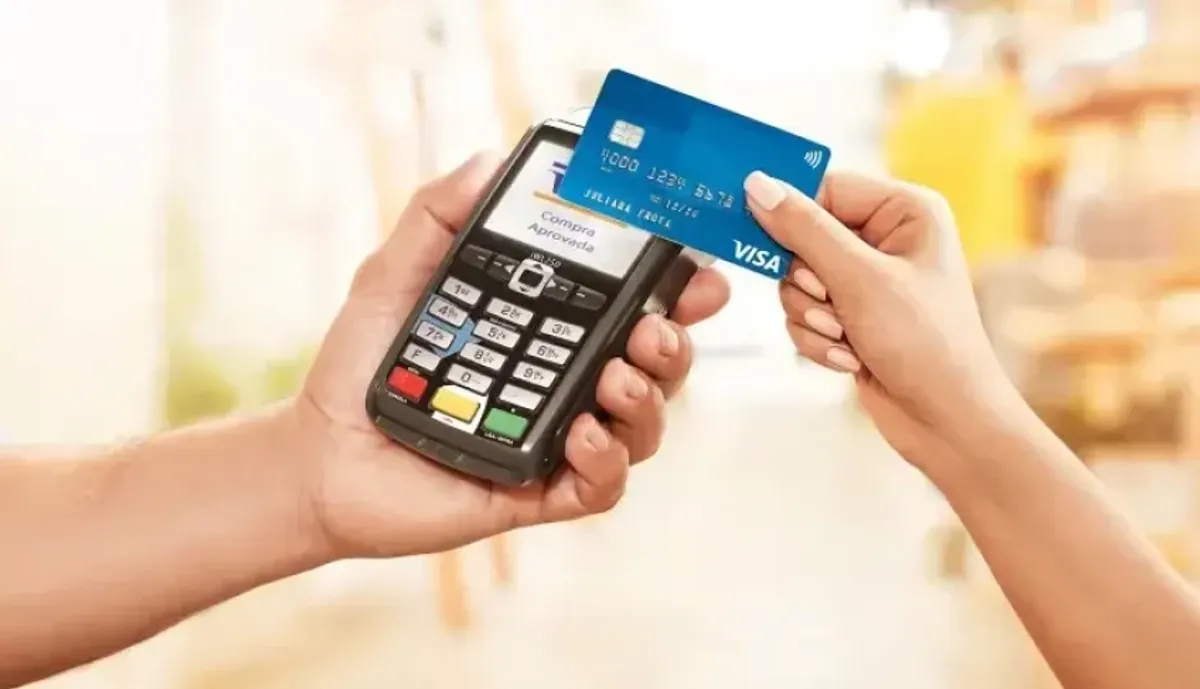 Empreendedor segurando cartão de crédito e analisando documentos financeiros em pequena empresa