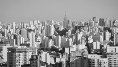 Pessoa pagando IPTU de 2026 com cartão de crédito usando smartphone e boleto impresso