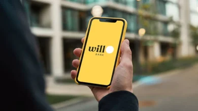 Smartphone exibindo aviso de liquidação do Will Bank com prédio institucional desfocado ao fundo