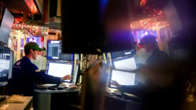 Sala de pregões com telas mostrando queda do petróleo e índices, operadores ao fundo