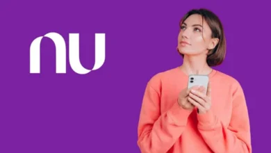 Smartphone mostrando aplicativo Nubank em primeiro plano; edifício do Banco Central ao fundo desfocado