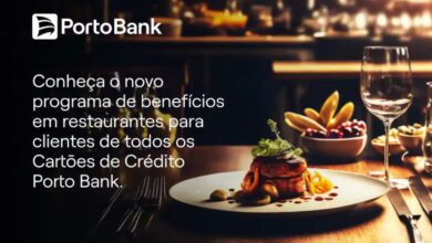 Mesa de restaurante com pratos e um cartão Porto Bank à vista, cena editorial em ambiente gastronômico